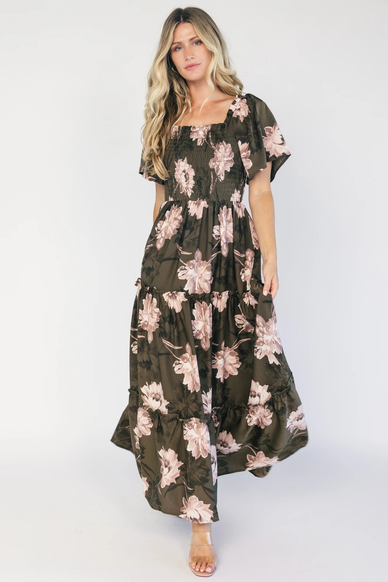Dark olive floral maxi dress with a smocked bodice, square neckline, flutter sleeves, and a tiered ruffle skirt.