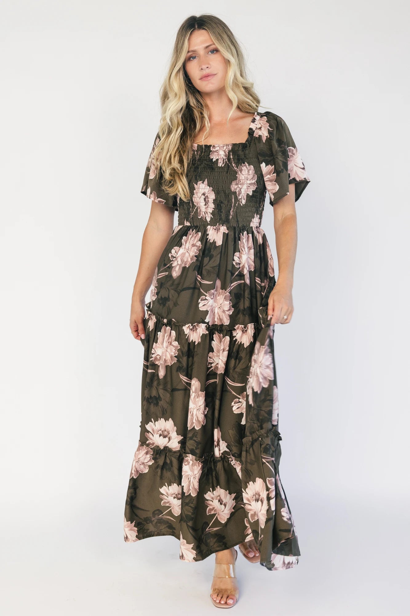 Dark olive floral maxi dress with a smocked bodice, square neckline, flutter sleeves, and a tiered ruffle skirt.