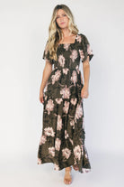 Dark olive floral maxi dress with a smocked bodice, square neckline, flutter sleeves, and a tiered ruffle skirt.
