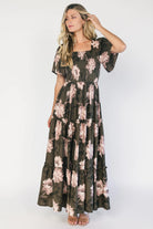 Dark olive floral maxi dress with a smocked bodice, square neckline, flutter sleeves, and a tiered ruffle skirt.