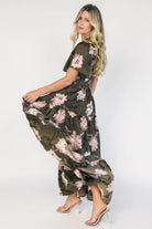 Dark olive floral maxi dress with a smocked bodice, square neckline, flutter sleeves, and a tiered ruffle skirt.