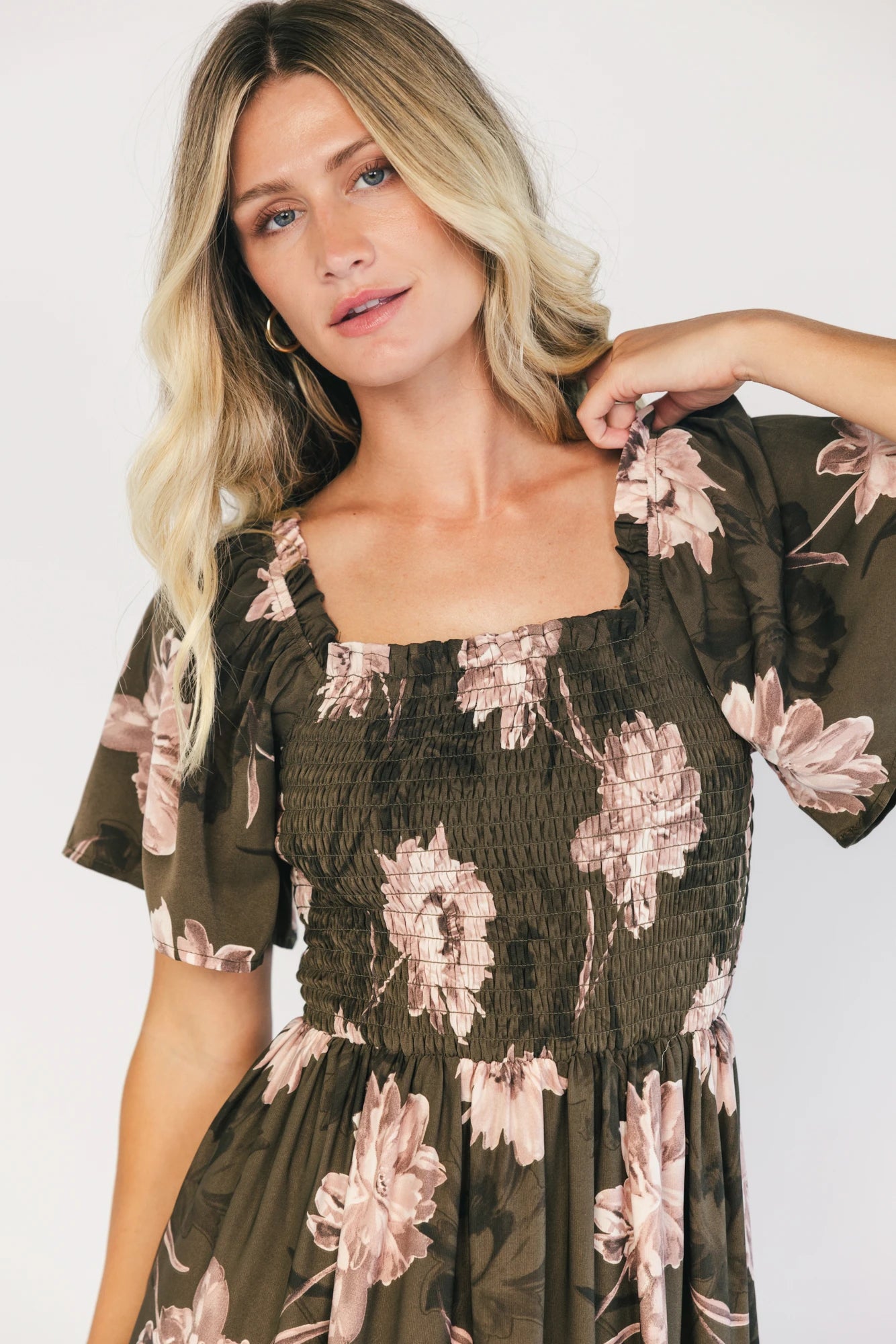 Dark olive floral maxi dress with a smocked bodice, square neckline, flutter sleeves, and a tiered ruffle skirt.