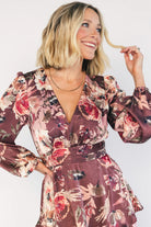 Clove satin maxi dress with a mauve floral print, V-neckline, short sleeves, a smocked back, and a flowing tiered ruffle skirt.