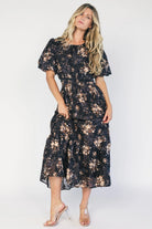 Model wearing a black floral midi dress with a round neckline, puff sleeves, and a smocked waist.