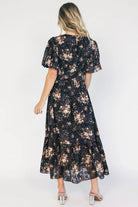 Model wearing a black floral midi dress with a round neckline, puff sleeves, and a smocked waist.