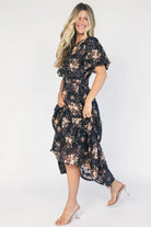 Model wearing a black floral midi dress with a round neckline, puff sleeves, and a smocked waist.