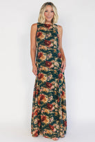 Model wearing a topaz floral maxi dress with a high round neckline, sleeveless bodice, and an open back with a sash tie.