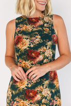 Model wearing a topaz floral maxi dress with a high round neckline, sleeveless bodice, and an open back with a sash tie.