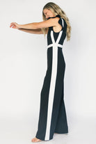 Model wearing the Lumina Ruffle Jumpsuit in Black + Ivory featuring a sleeveless ruffle-trim bodice, defined waist, and flowing wide-leg pants.