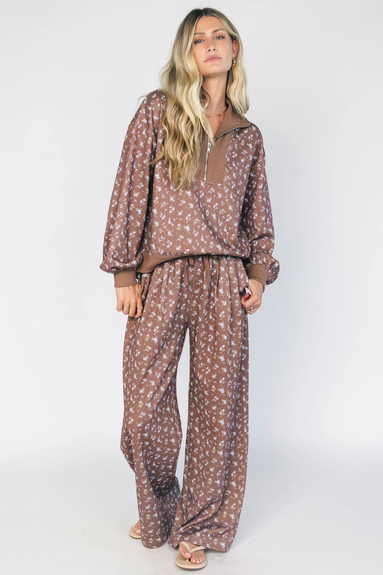 Model wearing the Diana Lounge Set in Brown Floral featuring a matching long-sleeve half-zip top and wide-leg pants.