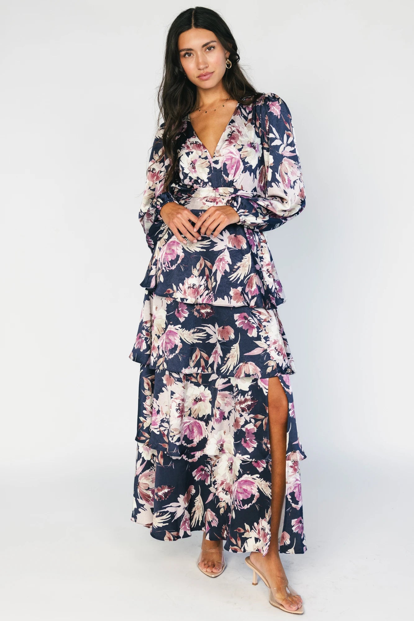 Model wearing the Montrouge Tiered Satin Maxi Dress in Navy + Lilac Floral featuring a V-neckline, short flutter sleeves, a smocked back, and a flowing tiered satin maxi skirt with a navy background and lilac floral print.