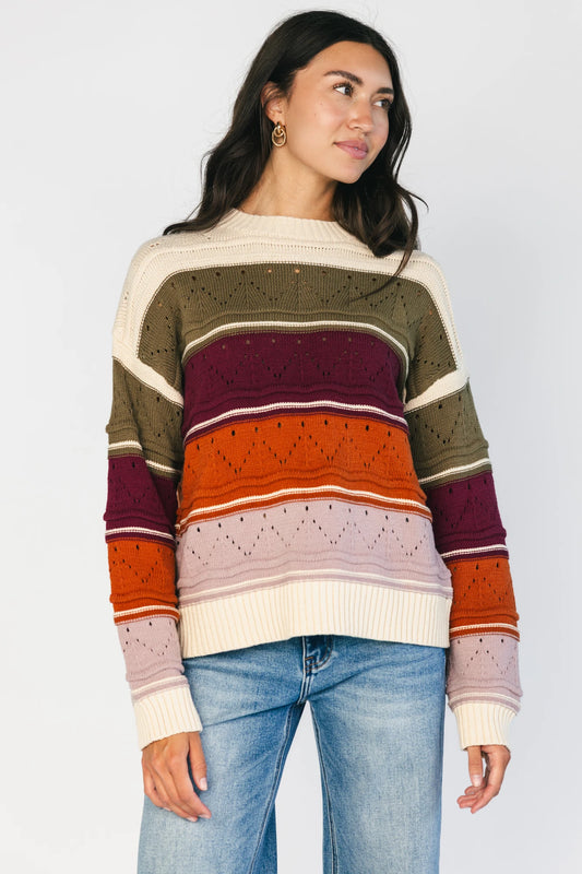 Ivory striped sweater with green, mulberry, rust, and purple horizontal stripes, a round neckline, dropped shoulders, long sleeves, and a relaxed fit.