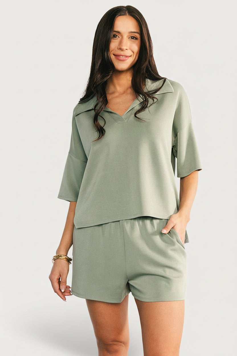 Model wearing green Ana collared V‑neck top and matching elastic‑waist shorts, relaxed fit, front view.