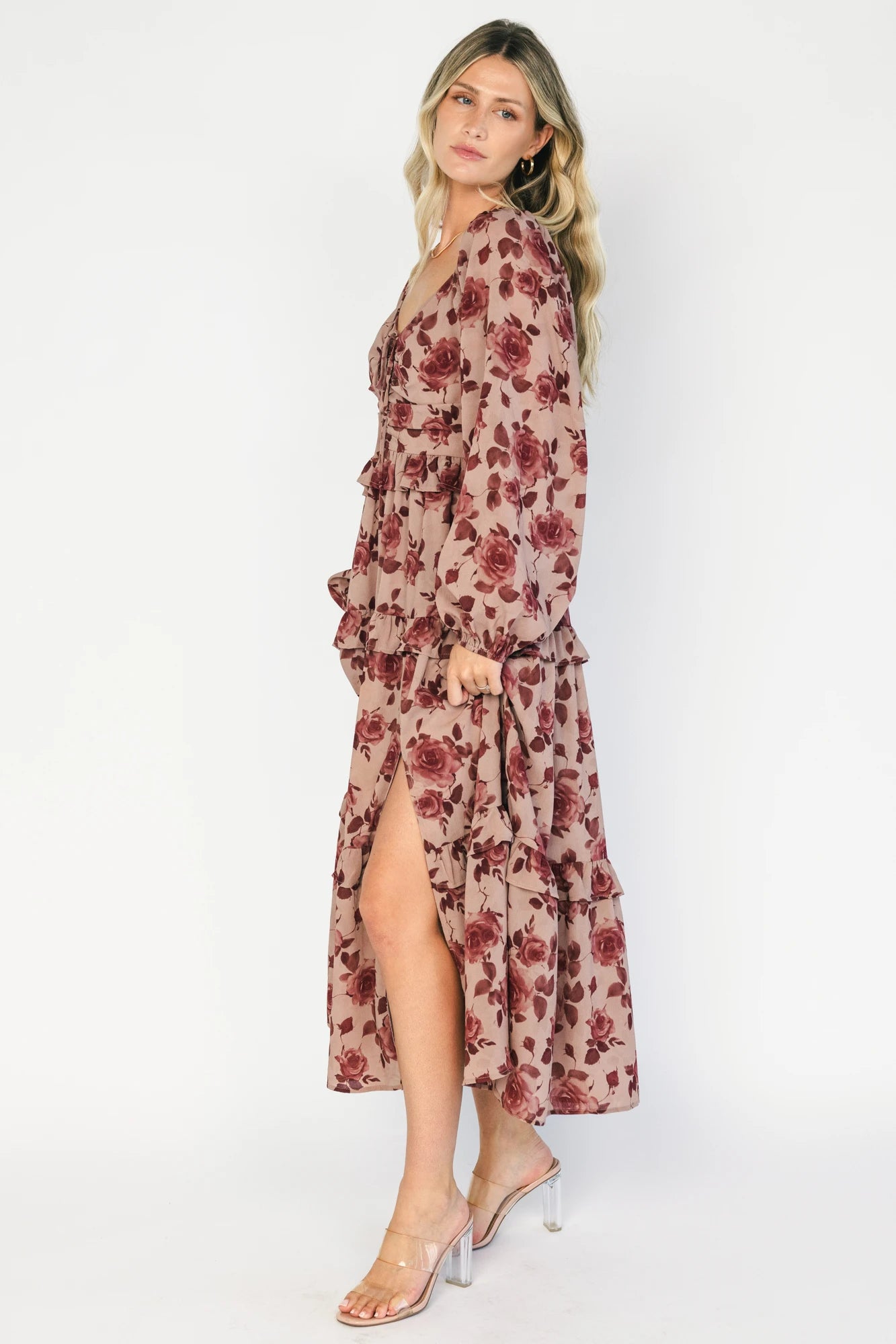 Model wearing a dusty mauve floral maxi dress with a sweetheart neckline, adjustable tie-front bust, and long sheer sleeves.