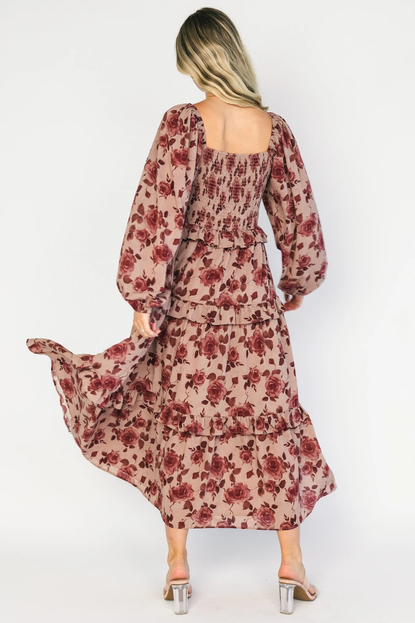 Model wearing a dusty mauve floral maxi dress with a sweetheart neckline, adjustable tie-front bust, and long sheer sleeves.