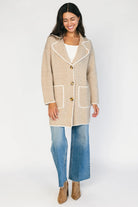 Taupe collared knit cardigan with cream contrast trim, a button-front closure, long sleeves, and two front patch pockets in a relaxed, shirt-style silhouette.