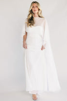 Front view of Serafina strapless sweetheart gown in off white, pleated maxi skirt and removable chiffon cape overlay.