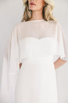 Back view showing button closure at back neck, zip closure, and removable chiffon cape draping over shoulders.