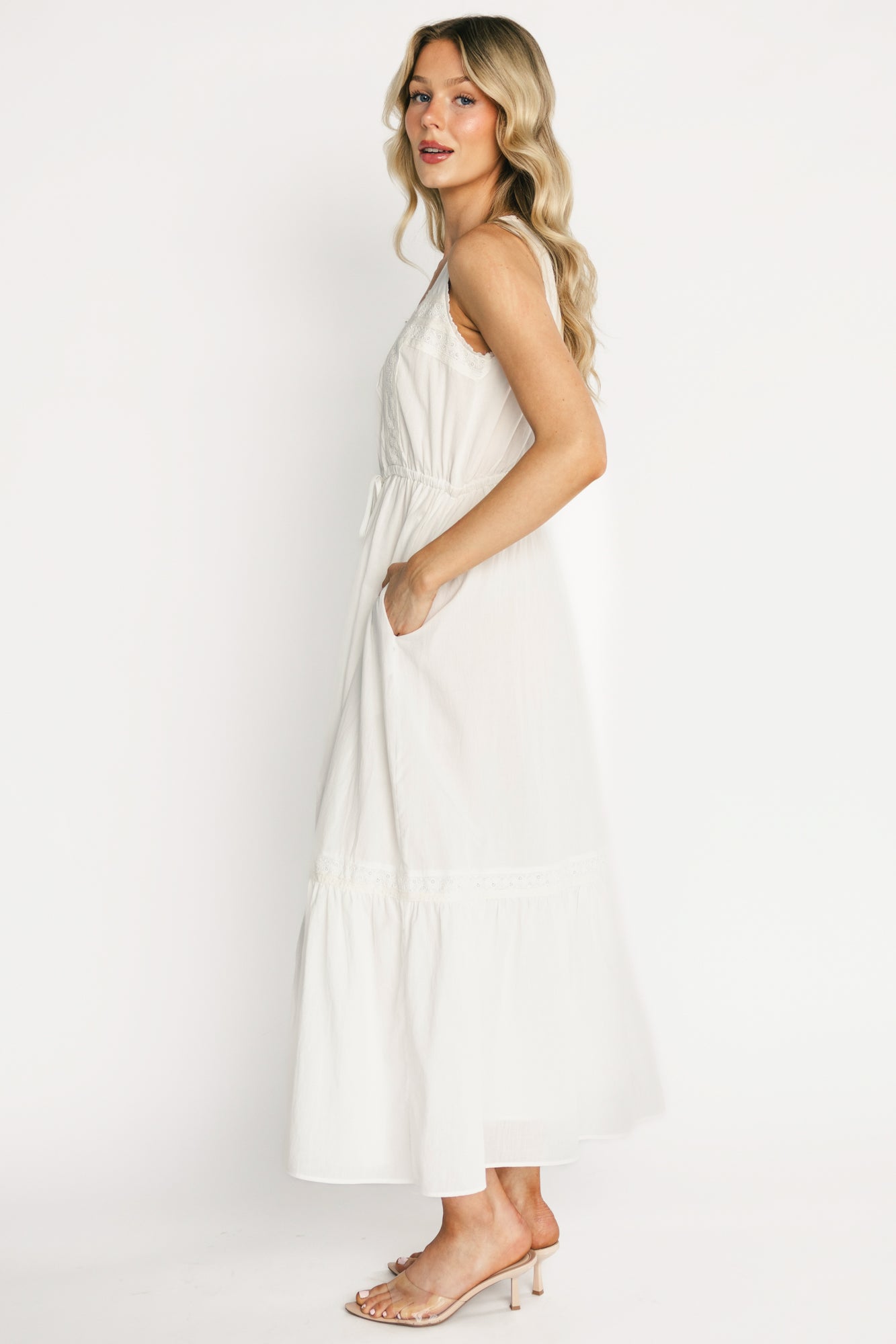 Side view of off-white Blanche midi dress highlighting tank sleeves, adjustable drawstring waist, and the flowing tiered midi skirt with lace detail.