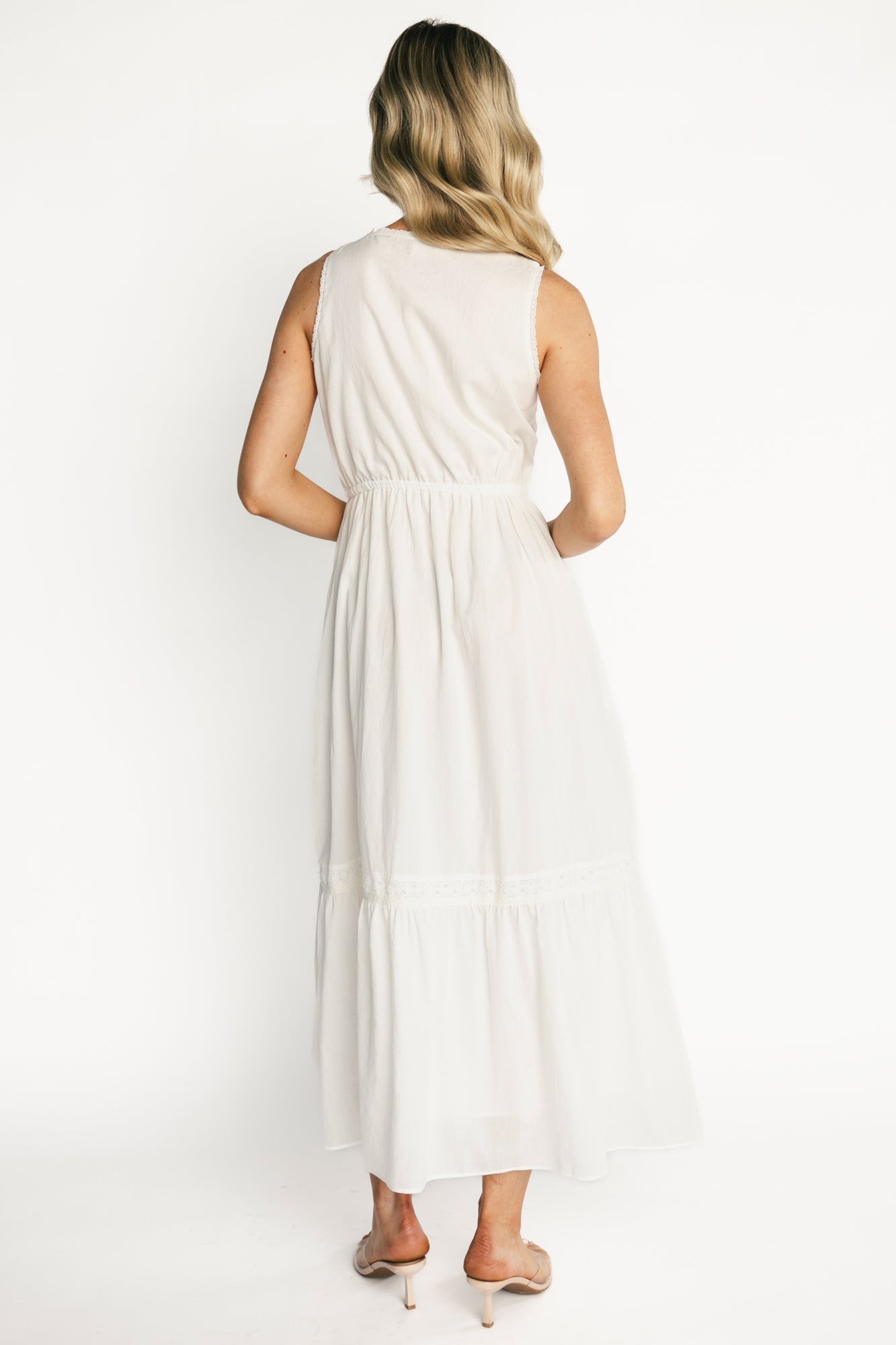 Full-length shot of Blanche midi dress on model showing silhouette, tiered skirt movement, and lace-trim hem in natural daylight.