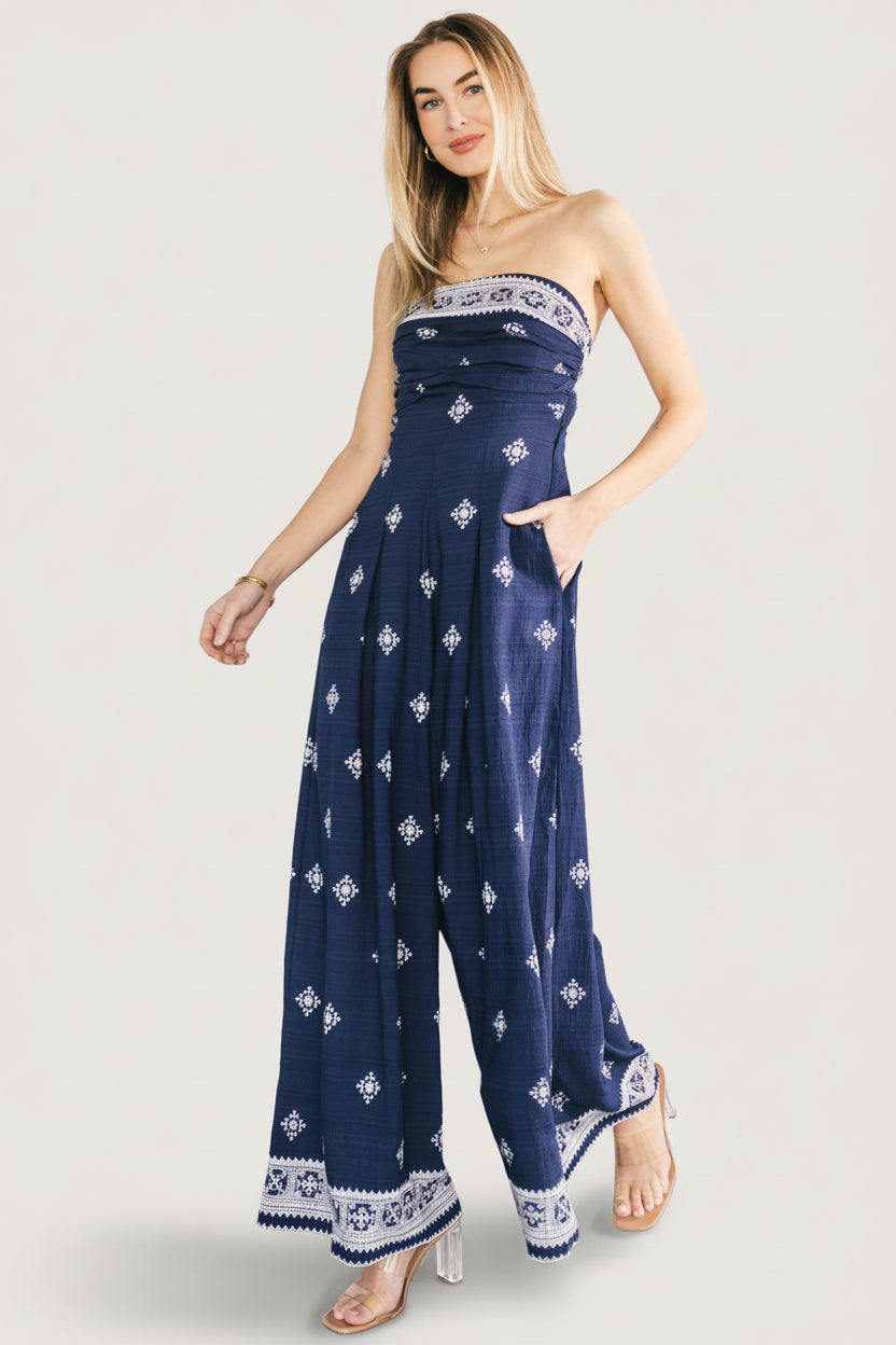 Front view of Córdoba strapless wide-leg jumpsuit in navy with off-white abstract print, showing strapless neckline and flowing silhouette.
