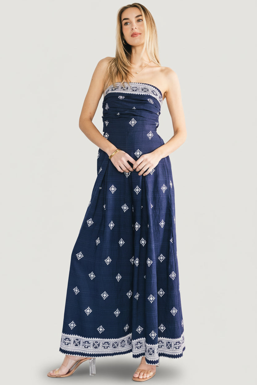 Model wearing Córdoba strapless jumpsuit full length, demonstrating the wide-leg shape and navy abstract print in natural light.