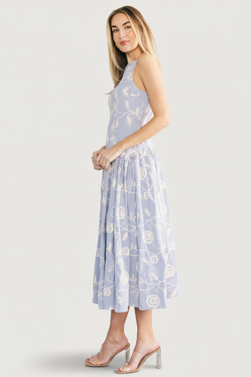 Full-length image of model wearing Shea Embroidered Dress in blue stripe, demonstrating midi length, movement from pleats, and sleeveless square-neck design.