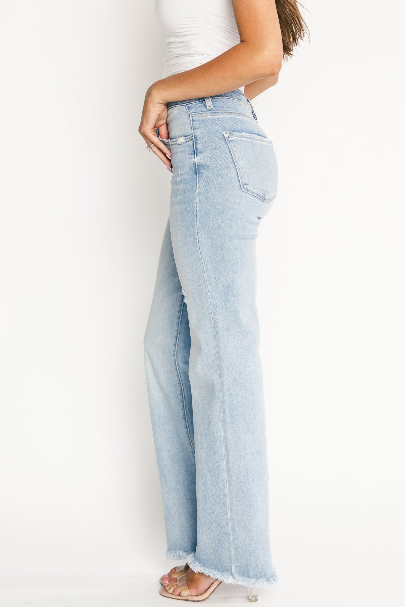Back view of model wearing Allure straight jeans showing back pocket distressing, seat fit, and cropped length with frayed hem finish.