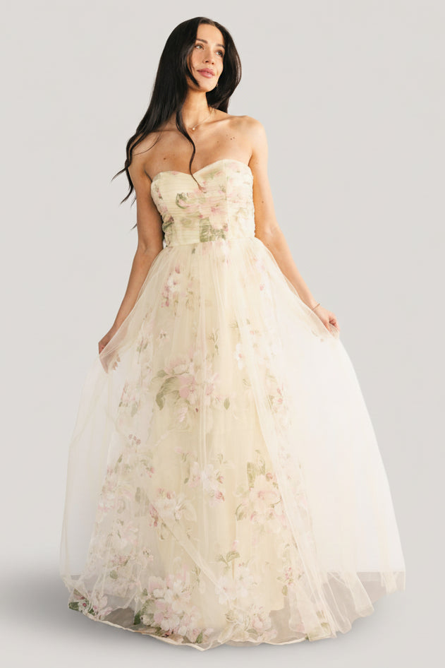 Back view of the Carlotta gown showing the back zipper, fitted bodice, and silhouette of the layered tulle skirt in soft yellow floral.