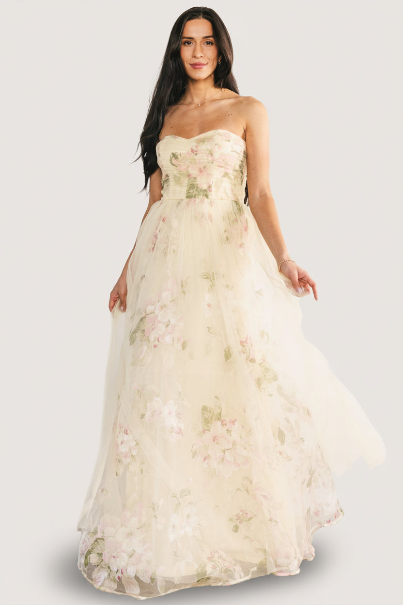 Full-length front view of the Carlotta tulle gown in soft butter-yellow floral print, strapless sweetheart neckline and flowing layered skirt, model pose.