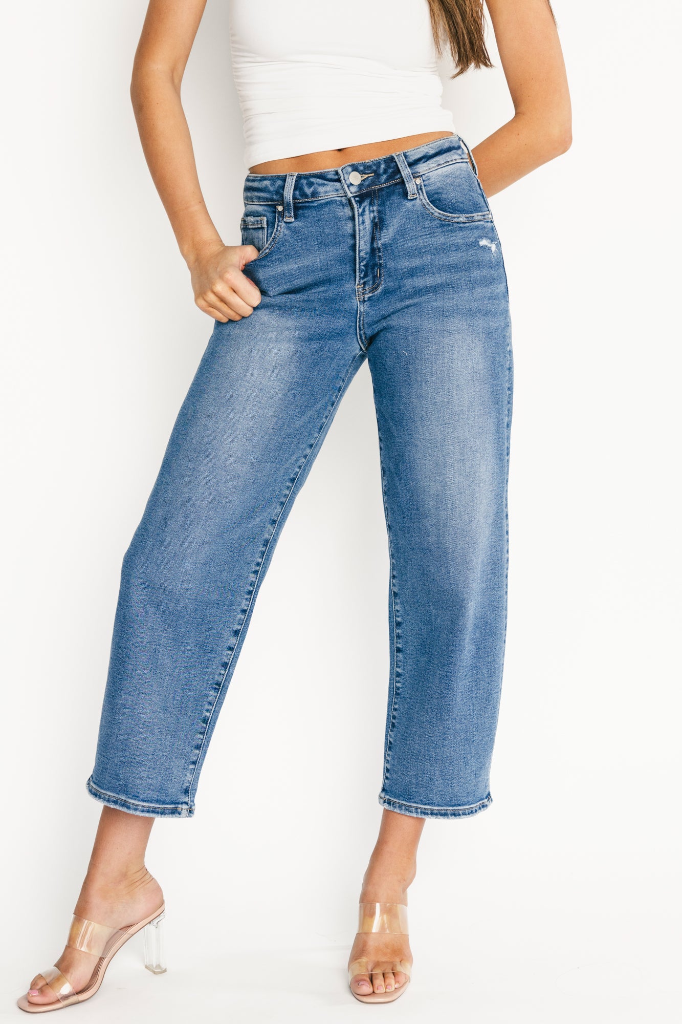 Front view of Lumi medium-wash high-rise crop barrel jeans on model, showing light distressing, button-and-zip fly, and front pockets; cropped above ankle.