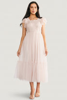 Back view of Elowyn midi dress showing the smocked back panel for stretch, unlined sheer sleeves, and the single-tier skirt in a soft natural tone.