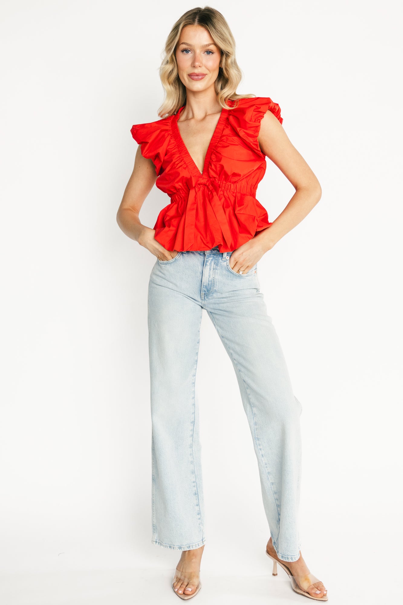 Detail shot of the Norma top fabric and ruffle edge in coral red, showing cotton texture and stitched peplum finish.