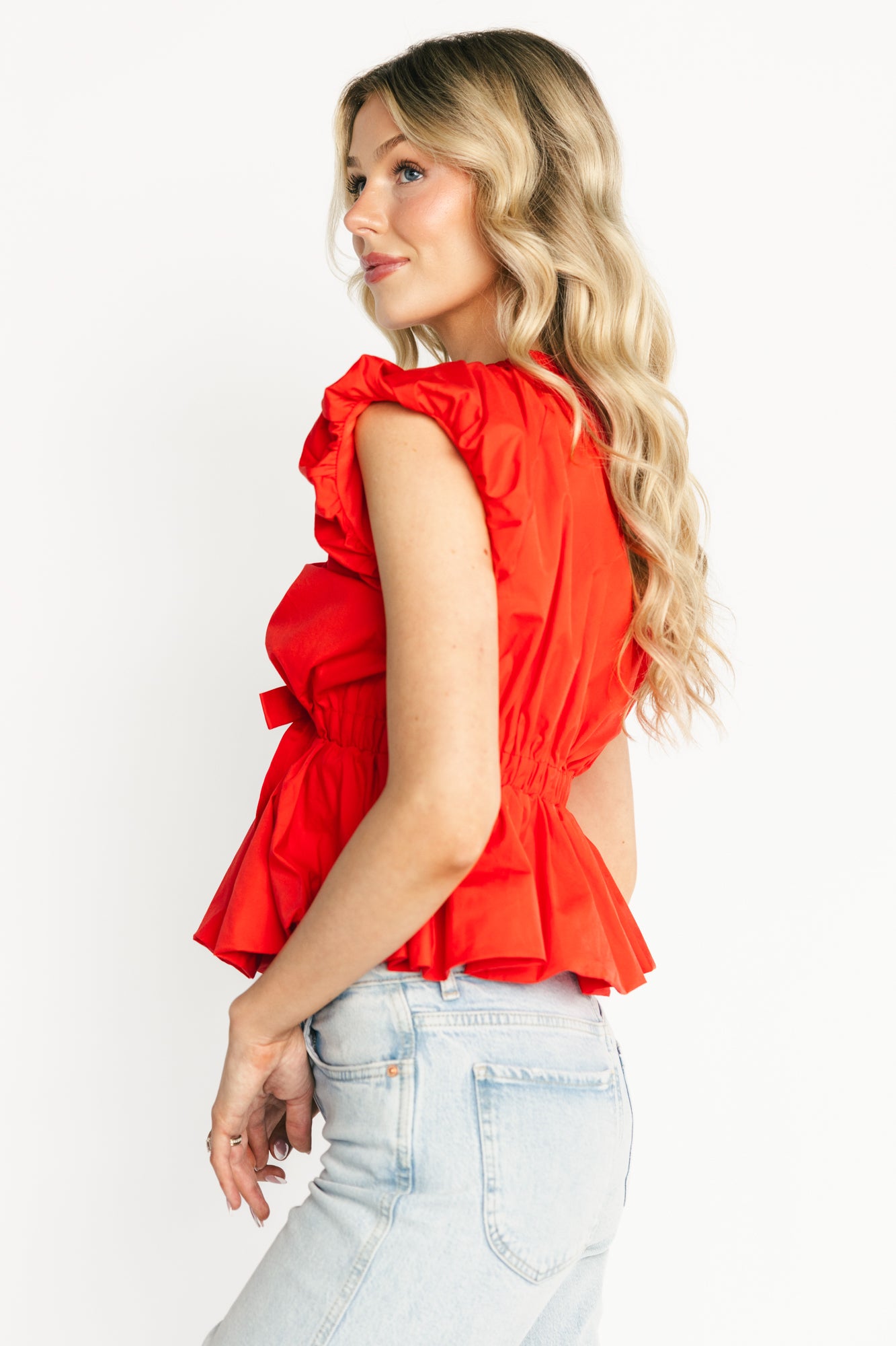 Close-up of the Norma top showing gathered detailing at the bodice, deep elastic V-neck and the front tie detail in coral red.