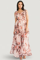 Side view of blush floral chiffon Macey Maxi Dress highlighting adjustable self-tie straps and the dress' graceful drape in motion.