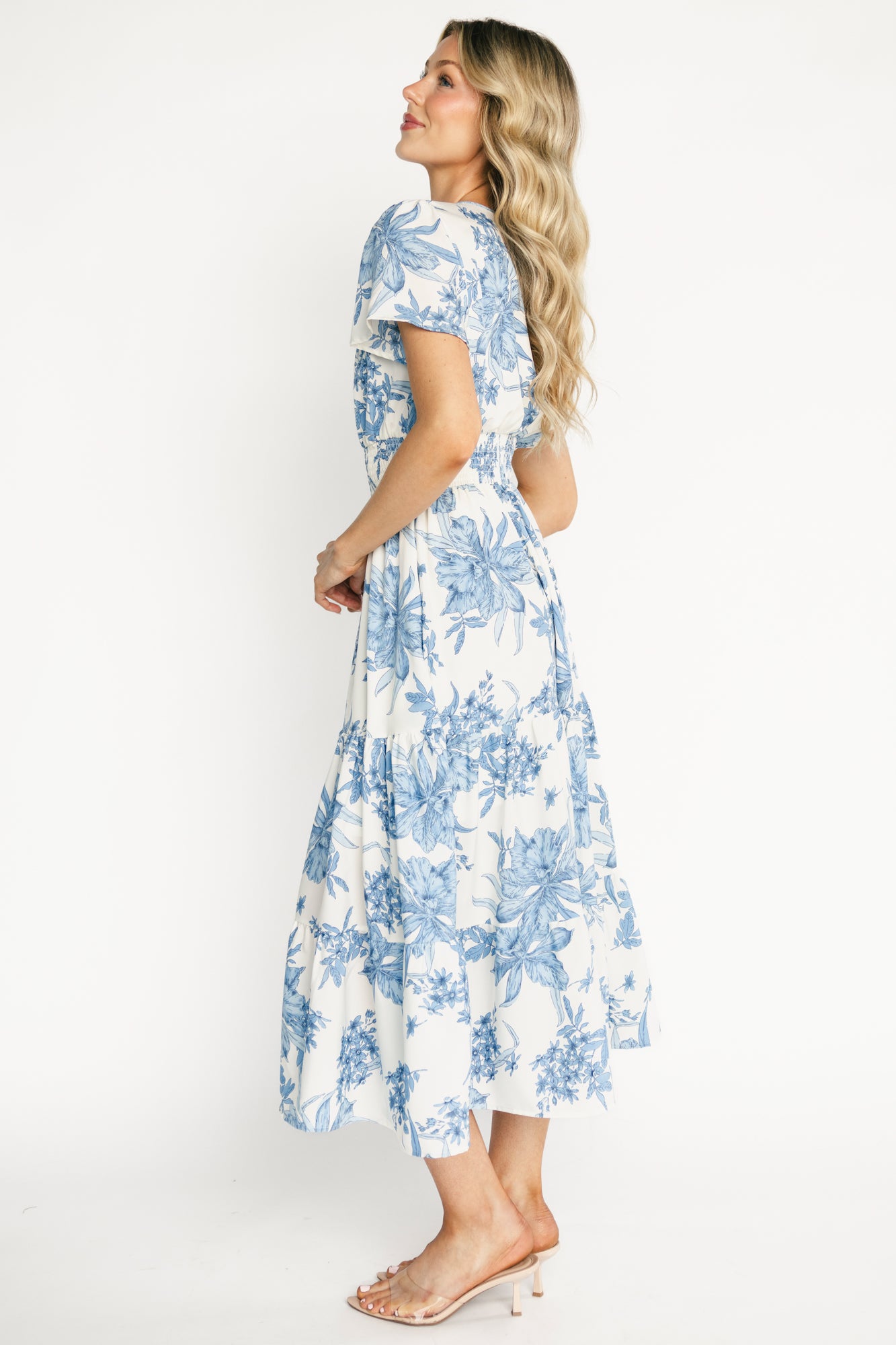 Close-up detail of the smocked waistband and partial lining on the Holland dress, highlighting stitch texture and blue floral print on off-white.