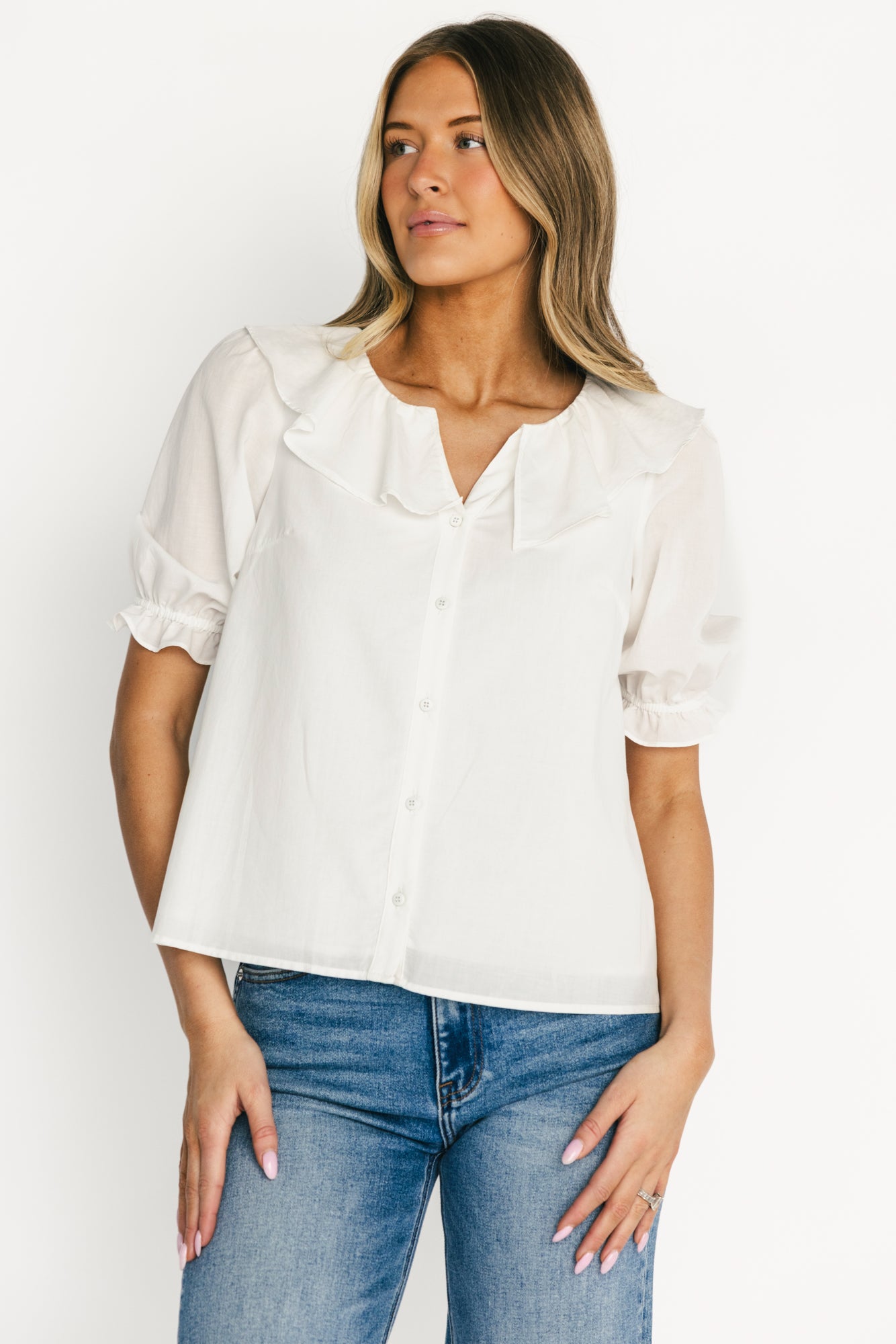Model front view wearing off-white Daisy Ruffle Button-Up Top, showing ruffle V-neck, button front, and short elastic ruffle sleeves.
