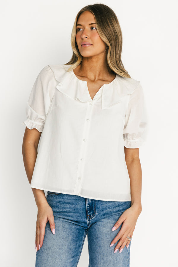 Model front view wearing off-white Daisy Ruffle Button-Up Top, showing ruffle V-neck, button front, and short elastic ruffle sleeves.