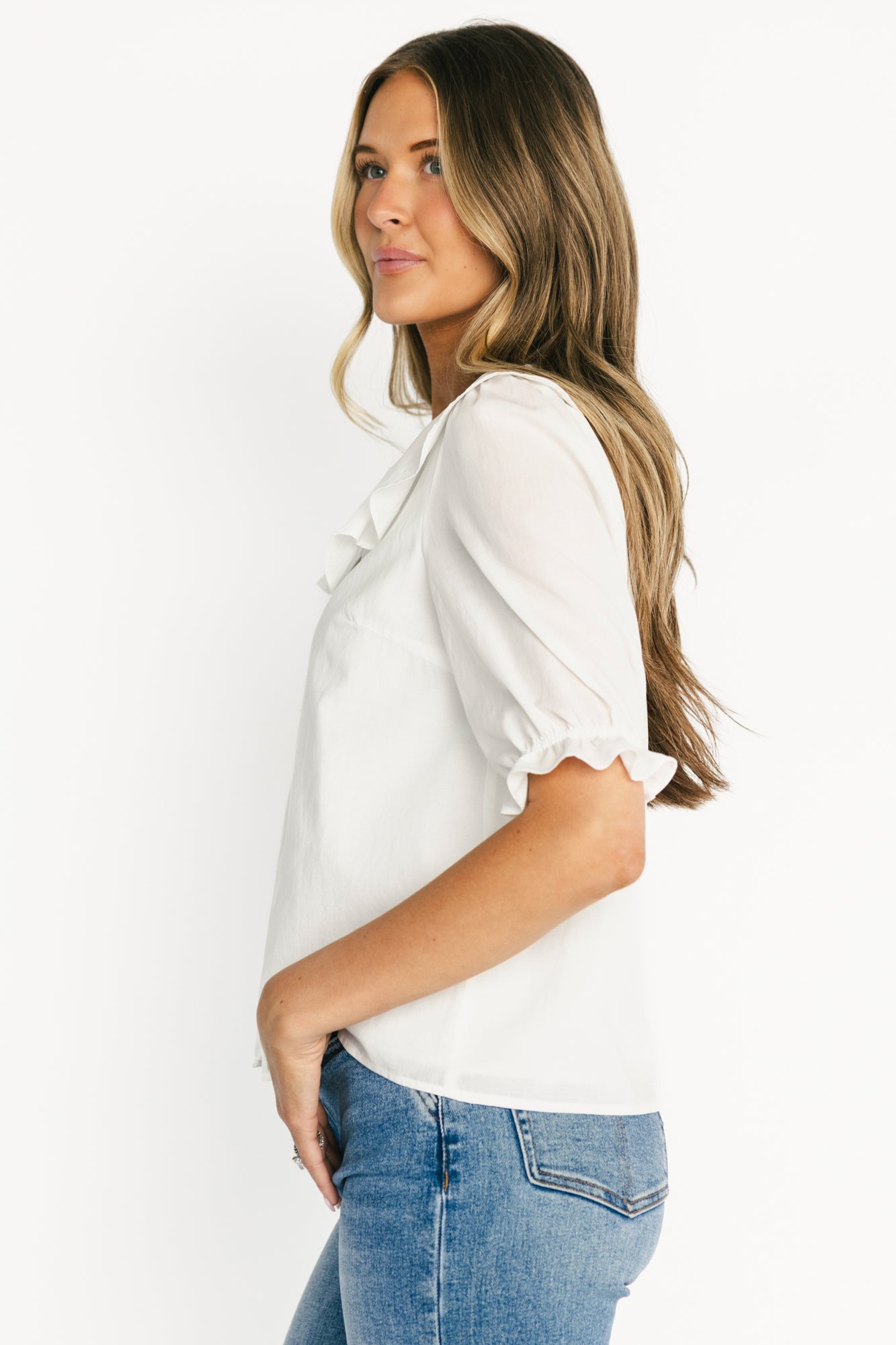 Styled outfit shot pairing the off-white Daisy Ruffle Button-Up Top with light-wash denim, showing length and versatile styling options.