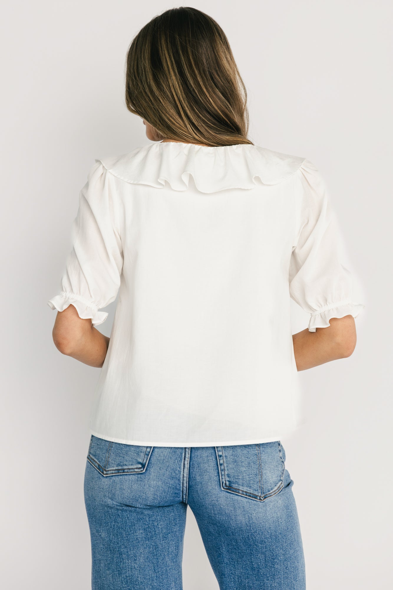 Detail close-up of short sleeve with elastic ruffle cuff on off-white Daisy Ruffle Button-Up Top, showing finish and fabric weave.