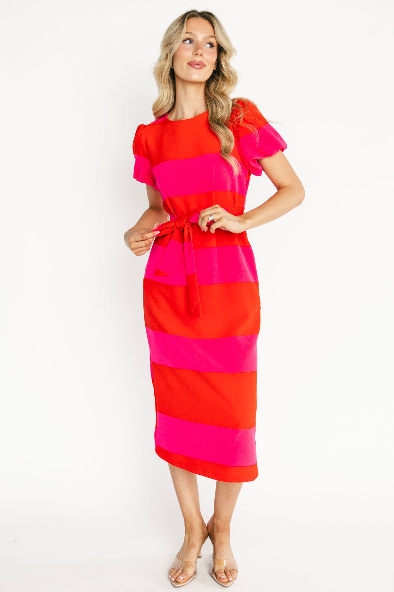 Front view of Andi Striped Midi Dress in red and pink chiffon with high round neckline, puff sleeves, removable waist sash, and midi hem length, on model.