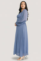 Lifestyle shot of the Dione georgette midi dress in dusty blue, showing sleeve cuff detail and the dress's flattering silhouette.