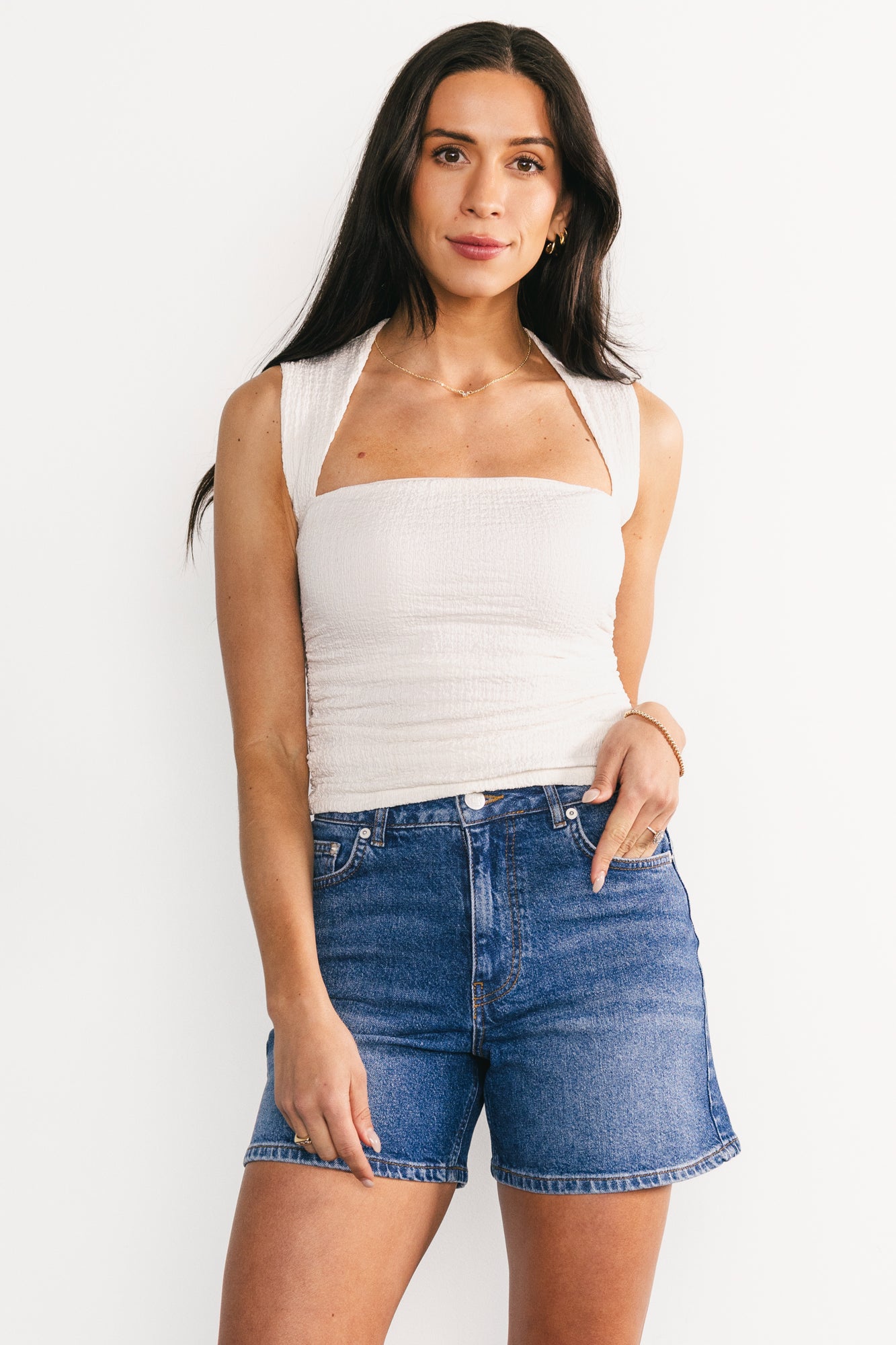 Side view of Lennon High-Rise Jean Shorts in medium wash, highlighting short length, high-rise silhouette, and frayed raw-edge hem.