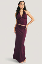 Close-up of the halter top in mulberry, showing V-neckline, side ruching, and bust dart detail in stretch jersey fabric.