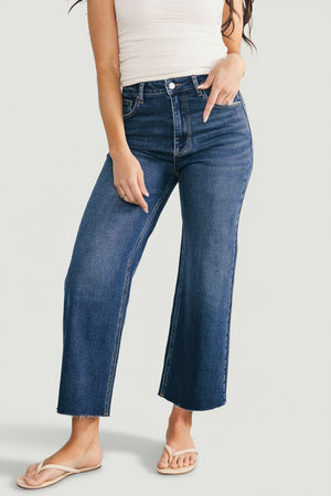 Model wearing dark wash Kirby high-rise wide-leg jeans, front view showing cropped raw hem, subtle distressing, and relaxed silhouette for casual styling.