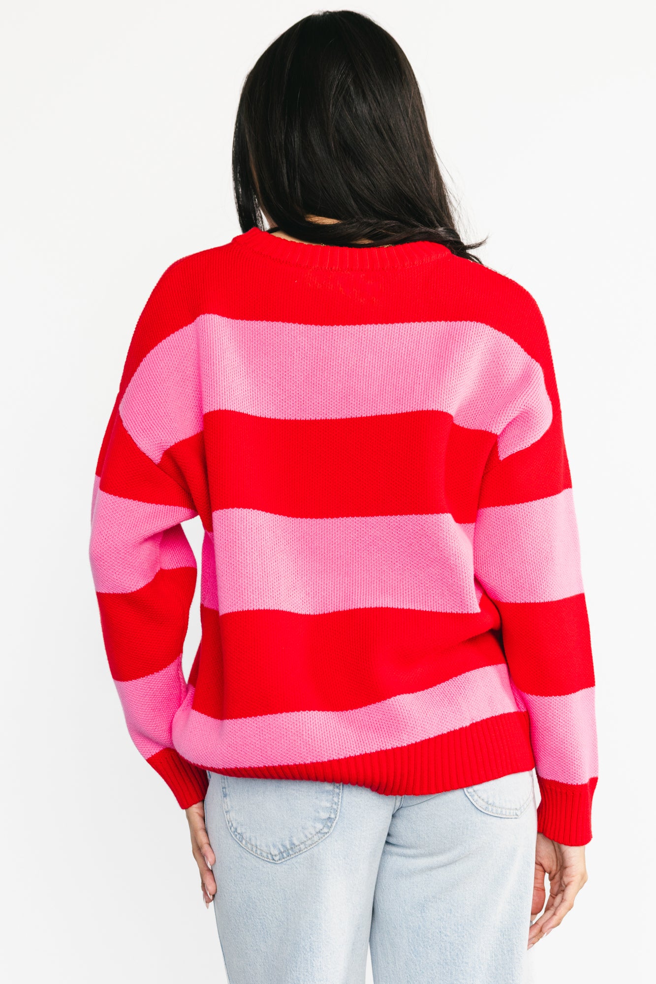 Flat-lay image of the Amour Striped Sweater in pink and red, laid flat to show full stripe pattern, round neckline, and ribbed edges.