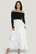 Front view of Maelie Tiered Maxi Dress on model; black ribbed off-shoulder sweater bodice with white tiered satin maxi skirt, full length.