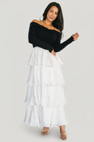 Detail photo of the white satin tiered skirt and hem ruffles, demonstrating volume and refined finish.
