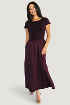 Styled full-length image of Angelique Midi Dress with accessories, illustrating versatile day-to-night outfit in deep mulberry