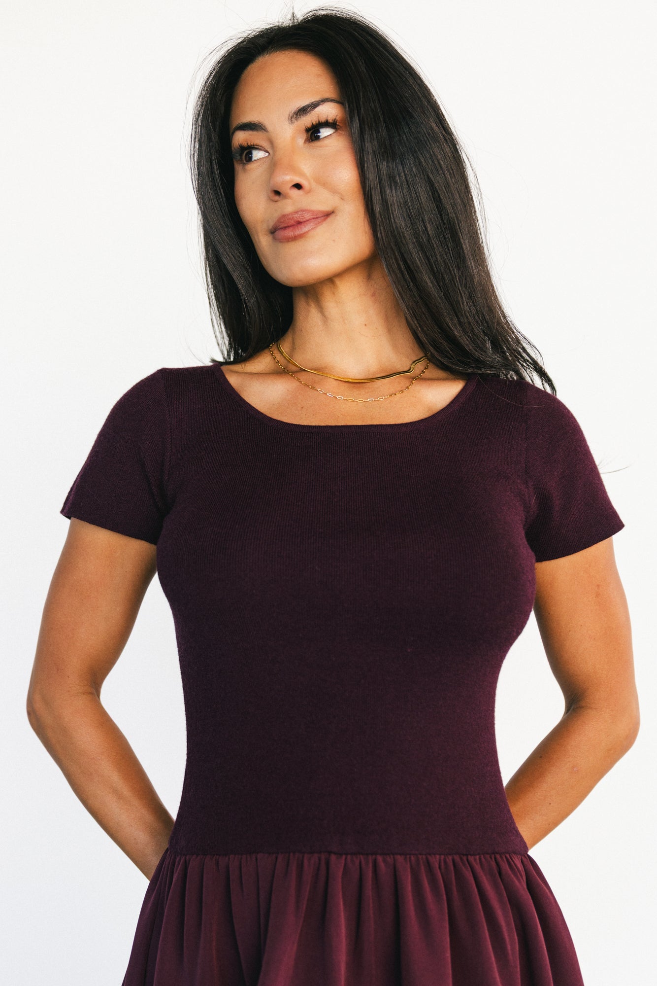 Back view of model in Angelique Midi Dress showing round neckline, elastic drop waist, and flowing midi skirt in deep mulberry
